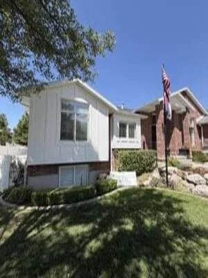 White modern siding addition on brick home with new windows and landscaping in Ogden