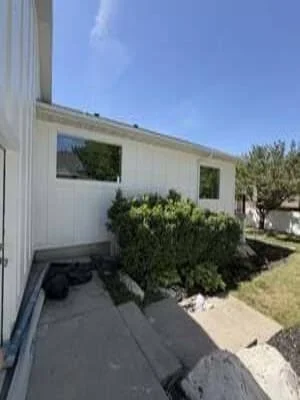 White metal-sided mobile home with new landscaping and concrete foundation work